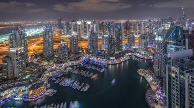 Dubai Marina gökdelenleri ve Jumeirah göl kulelerini aydınlattı ve Birleşik Arap Emirlikleri 'nin en üst düzey hava gece zaman çizelgesinden panoramik görüntüler elde etti. Yolda trafik ve yüzen yatlar.