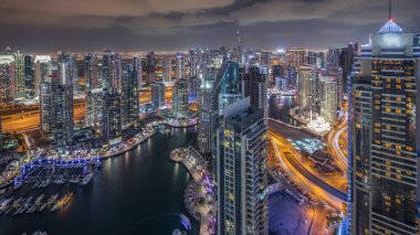 Dubai Marina gökdelenleri ve Jumeirah göl kulelerini aydınlattı ve Birleşik Arap Emirlikleri 'nin en üst düzey hava gece zaman çizelgesinden panoramik görüntüler elde etti. Yolda trafik ve yüzen yatlar.