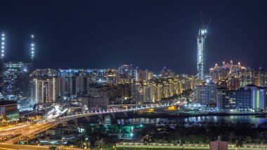 Palm Jumeirah Karayolu köprü hava gece timelapse. Trafik ve şantiye ile Internet şehirden görünüm. Dubai, Birleşik Arap Emirlikleri