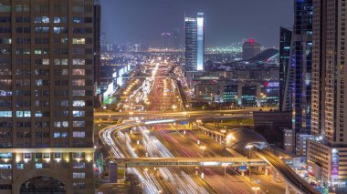 Şeyh Zayed Road hava gece timelapse geçiş ile Skyline internet şehir. Dubai'de bir otoyol ve metro hattı üzerinde trafik ile Işıklı gökdelenler