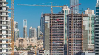 Arka planda Dubai, Birleşik Arap Emirlikleri 'nin merkezi olan Business Bay' de mavi ve temiz gökyüzü olan özel makineler ve vinçlerle modern inşaat.