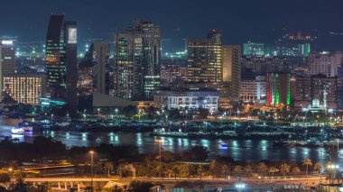 Gece Deira ve Dubai Creek, Birleşik Arap Emirlikleri 'nde yüzen gemiler ve yatlarla şehrin ve nehrin hava görüntüsü