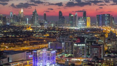 Şehir merkezinde büyük gökdelenler ve onlardan gelen ışıklar ve renkli gökyüzü, Dubai, Birleşik Arap Emirlikleri ile finans bölgesi Timelapse 'nin havadan görünüşü