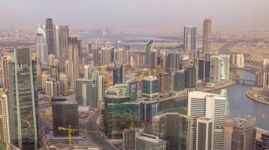 Dubai'deki iş bölümü kulelerinin panoramik havadan görünümü akşam saatinde. Yapım aşamasındaki bazı gökdelenler, kanal ve yeni kulelerin çatı görünümü.