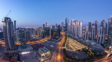 Dubai İş Sahası Panorama 'sı gece gündüz geçiş zamanı. Gökdelenleri ve hareket eden uzun gölgeleri olan gökdelenler. Gün doğarken trafik vardı..