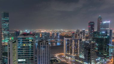 İş hanı gece kuleleri aydınlatıyordu. Kanal yakınlarındaki bazı gökdelenlerin çatı manzarası ve inşaat halindeki yeni kuleler. Yollarda trafik ve pencerelerde ışıklar