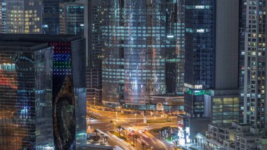 Dubai 'deki bir kavşakta gece vakti hava üstü şehir trafiği. Yukarıdan yol ayrımı, otomobil trafiği ve gökdelenler