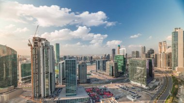 Dubai 'nin iş hanı kuleleri sabahları havadan kontrol ediliyor. Bazı gökdelenlerin çatı manzarası ve inşaat halindeki yeni kuleler. Mavi gökyüzünde bulutlar ve yollarda trafik