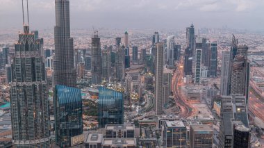 Dubai Şehir Merkezi gökdelenleri ve Burj Halife 'nin gece gündüz geçiş yaptığı fütüristik şehir manzarası. Gündoğumundan önce çatıdan modern kuleleri ve inşaatı olan sabah manzarası