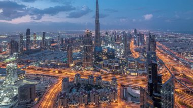 Dubai Şehir Merkezi 'nin gökdelenleri ve Burj Halife' nin gece gündüz gökdelenleri ile fütüristik şehir manzarası. Gündoğumundan önce çatıdan modern kuleleri ve inşaatı olan sabah manzarası