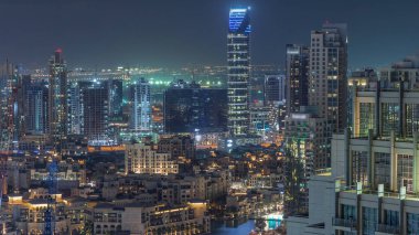 Dubai şehir merkezi gökdelenleri gece vakti fıskiyeleri ve Dubai, Birleşik Arap Emirlikleri eski kasaba geleneksel evleri ile muhteşem bir hava manzarası. Aydınlatılmış modern kuleler ve inşaat alanı