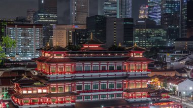 Singapur Çin Mahallesi 'nde gece vakti Buda Dişi Kalıntısı Tapınağı canlanır. Arka planda şehir kuleleri gökdelenleri vardır. Tapınak gökdelenler ve kulelerle aydınlık