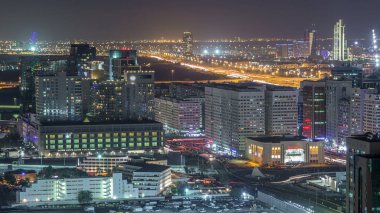 Abu Dabi şehir merkezinin gökyüzü çizgisi. Gece vakti gökdelenler aydınlatılmış ve yol trafiği var.