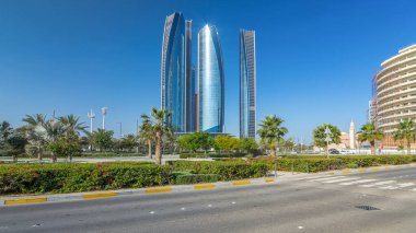 Ebu Dabi 'nin gökdelenleri Etihad Kuleleri' nin binaları zaman atlamalı. Avuç içleriyle ve trafiğiyle park et. Güneş cam yüzeyden yansıyor. Birleşik Arap Emirlikleri