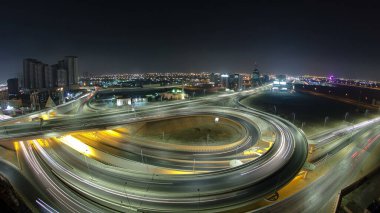 Ajman 'da büyük bir yol kavşağında trafik vardı. Gece vakti çatıdan panoramik manzara vardı. Birleşik Arap Emirlikleri 'nde üst geçitle kesişen birçok araba var..