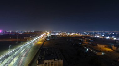Panorama, Ajman hava sahasında büyük bir kavşakta trafiği gösteriyor. Gece vakti çatıdan görünüyor. Birleşik Arap Emirlikleri 'nde üst geçitle kesişen birçok araba var..