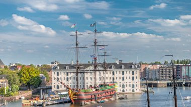 Denizcilik Müzesi 'nin zamanlaması ve Amsterdam' ın teknesinin kopyası yakında. Bulutlu mavi gökyüzü. Kültürel aktiviteleri, kanalları ve köprüleri meşhurdur. Amsterdam, Hollanda
