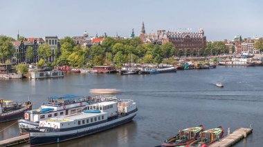 Oosterdok Limanı 'ndaki iskelede botları olan Amsterdam gökyüzü manzarası. Amsterdam Centraal İstasyonu ve Scheepvaarthuis yakınlarındaki geleneksel Hollanda mimarisi. Amsterdam, Hollanda