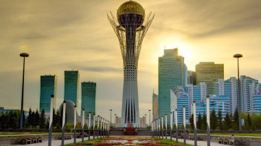 Astana 'nın başkenti Kazakistan' daki Bayterek Kulesi 'nde gün batımı için güzel bir zaman dilimi. Arka planda modern binalar ve gökdelenler var. Turuncu gökyüzü. Nur-Sultan şehri, Kazakistan