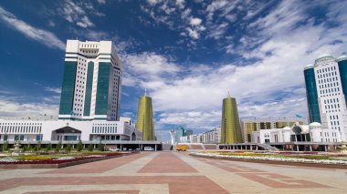 Nur-Sultan şehrinde Kazakistan Cumhuriyeti Senatosu 'nun inşa edilmesi. Ön planda çiçek açmış. Arka planda Nurzhol Bulvarı. Yazın mavi bulutlu gökyüzü