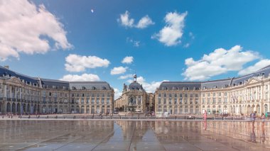 Place de la Bourse ve Miroir d 'eau hiperlapse Bordeaux, Fransa' da, tarihi mimariyi yansıtıyor. Turistler şehir simgesi ve çeşmenin tadını çıkarıyorlar. Trafik ve tramvay zamanı geçiyor..