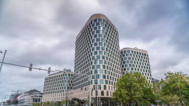 Baudouin Bulvarı, Brüksel, Belçika 'daki iş alanındaki trafik ve modern ofis binalarının zaman çizelgesi. Kavşağın yanındaki çağdaş kuleler bulutlu bir gökyüzünün altına park ederler.