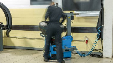 Profesyonel araba tamircisi otomobil tamir servisinin zaman ayarında tekerleği değiştiriyor. Makine dengeleyicisi ile dengeleyici tekerlek hizmet.