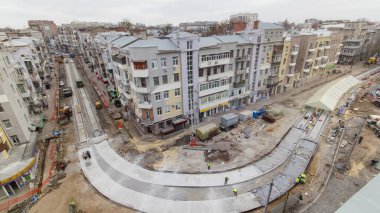 Yol yapımı için beton kaplayan bir sürü işçi ve mikser makinesi, vinç, traktör zaman ayarlı. Tramvay raylarının yeniden inşası. Bulutlu bir günde hava üst görünümü