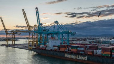 Barcelona 'nın deniz kargo limanı ve konteynır terminalinin günbatımı görüntüsü Montjuic Hill zaman atlaması, Barcelona, Katalonya, İspanya. Gemiler vinçlerle yükleniyor. Seyahat terminalinden görüntüle