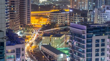 Dubai Marina havadan görünümden bir noktadan gece timelapse. Modern gökdelenler ve konut kuleleri parlayan windows ile aydınlatılmış. Yolda trafik