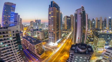 Dubai Yat Limanı hava görünümünü gece geçiş timelapse için bir noktadan günden güneş battıktan sonra. Modern gökdelenler ve konut kuleleri de akşam aydınlatılmış. Köprüde trafik