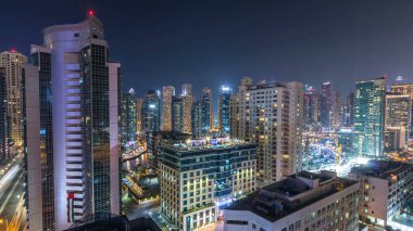 Gece görüş noktasından Dubai Marina 'nın hava görüntüsü. Parlayan pencerelerle aydınlatılmış modern gökdelenler ve konut kuleleri. Yoğun bir yolda trafik var.