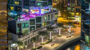 Dubai Marina havadan görünümden bir noktadan gece timelapse. Waterfront adlı mesire üzerinde yürüyen insanlar. Modern gökdelenler ve konut kuleleri parlayan pencerelerle aydınlatılmış