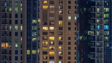 Çok öykülü modern cam ve metal kadar ışık gece timelapse bina konut içinde parlayan pencere eşiği. Daireler insanlar. Geceleri aydınlatılan evler. Dubai Yat Limanı ve Jbr, Birleşik Arap Emirlikleri