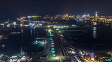 Palm Jumeirah Adası 'nın gece görüntüsü. Işıklı villaları, otelleri ve yatları olan en iyi panoramik manzara. Yeni gemi terminalinin inşa süreci