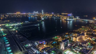 Palm Jumeirah Adası gece timelapse hava görünümünü. Üstten görünüm ışıklı Villa, otel ve yat ile. Yeni cruise terminal inşaat süreci