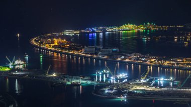 Palm Jumeirah Adası gece timelapse hava görünümünü. Villa, otel ve yat ile üstten görünüm. Yeni cruise terminal inşaat süreci