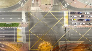 Bir büyük şehir gece timelapse bir yol kavşak hava üstten görünüm. Arabalar ve tramvay hattı ile UAE Dubai Yat Limanı bölgesinin kentsel peyzaj.