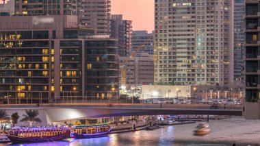 Alışveriş merkezinin yakınında turistlerin kaldığı yatlar ve tekneler Dubai Marina bölgesindeki bir köprünün altından geceyle gündüze geçiş zamanları. Akşam günbatımından sonra gökyüzü manzarası.