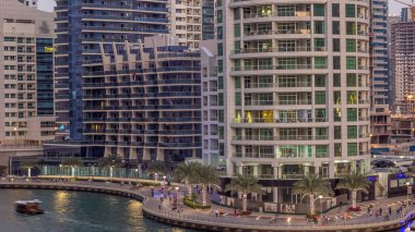 Geçen tekneler ve avuç içi gün gece ile promenade ile lüks Dubai Yat Limanı kanal timelapse geçiş, yukarıdan bakışta akşam güneş battıktan sonra Top. Dubai, Birleşik Arap Emirlikleri