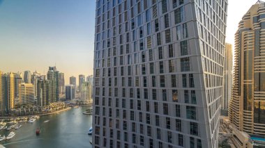 Dubai Marina gezinti alanı ve kanalı, gün batımından önce Dubai, BAE 'de yüzen yatlar ve teknelerle güzel bir hava manzarası. Akşam saatlerinde pencereli modern kuleler ve gökdelenler