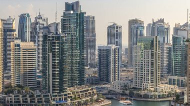 Dubai Marina 'nın güzel hava manzarası panorama ve kanalı. Dubai, BAE' de günbatımından önce yüzen yatları ve tekneleri var. Geceleri modern kuleler ve gökdelenler