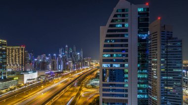 Dubai Yat Limanı timelapse fantastik çatı manzarası. Işıklandırılmış gökdelenler büyük bir şehrin gece, Birleşik Arap Emirlikleri. Havadan görünümden Jlt trafik ile Şeyh zayed yolu üzerinde