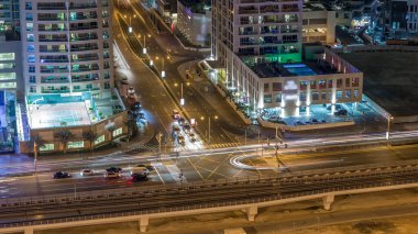 Bir büyük şehir gece timelapse bir yol kavşak hava görünümünü. Arabalar ve tramvay ile UAE Dubai Yat Limanı bölgesinin kentsel peyzaj