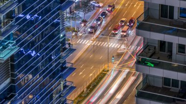 İki gökdelen arasındaki büyük bir şehirde gece vakti yol kesişiminin havadan görüntüsü. BAE 'nin Dubai Marina ve JBR semtlerinde arabalı şehir manzarası