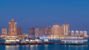 Katara Sahili 'nden gece gündüz görüntüsü. Gün batımından sonra Doha, Katar' da İnci 'ye geçiş zamanı. Yerleşim binaları ufuk çizgisi