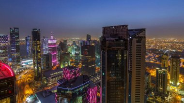 Batı Körfezi bölgesinin ufuk çizgisi Doha 'da günden geceye geçiş zamanı, Katar. Günbatımından sonra modern gökdelenlerin çatıdan görünüşü aydınlandı. Yolda trafik vardı.