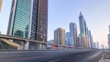 Dubai 'deki Sheikh Zayed Yolu' ndaki gökdelenler gün batımında trafik varken aşırı hızlanıyorlar. Panoramik hareket