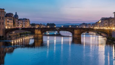 Ponte Santa Trinita 'nın (Kutsal Üçlü Köprü) alacakaranlık sahnesi gün batımından sonra suya yansıyarak Arno Nehri üzerinde geçiş zamanı. Floransa, Toskana, İtalya