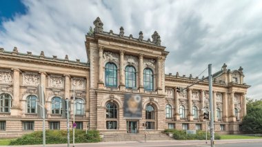 Hanover 'in Aşağı Saksonya Devlet Müzesi' nin trafik ve tarihi ön cephelerinin önünden geçen insanlar. Bulutlu gökyüzü, Almanya 'nın Niedersachsen zaman diliminde kültürel dönüm noktasını çerçeveledi